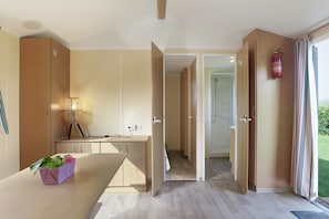 Une chambre d’hôtel moderne avec un bureau en bois, une plante, un extincteur et une vue sur l’extérieur.