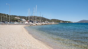 A beach with boats, clear water, and a hilly background. - Studio Apartment 'Vaso' with Mountain View, Wi-Fi and Air Conditioning (Nikiana)