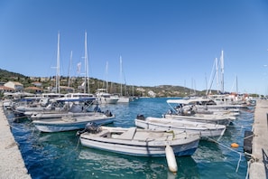 Uma marina com vários barcos atracados, c éu claro e paisagem montanhosa ao fundo.