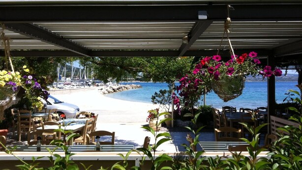 A seaside restaurant with outdoor seating overlooking a beach and the sea. - Studio Apartment 'Vaso' with Mountain View, Wi-Fi and Air Conditioning (Nikiana)