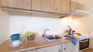 A kitchen with wooden cabinets, a sink, a stove, and a pot on the counter. - Studio Apartment 'Vaso' with Mountain View, Wi-Fi and Air Conditioning (Nikiana)