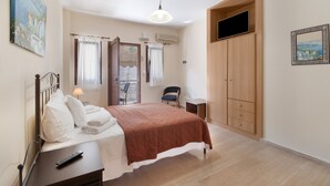 A bedroom with a bed, a bedside table, a chair, a wardrobe, and a painting on the wall. - Studio Apartment 'Vaso' with Mountain View, Wi-Fi and Air Conditioning (Nikiana)