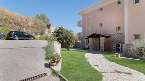 Um edifício residencial com calçada pavimentada, caminho de pedra e gramado bem cuidado.