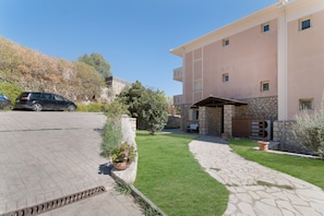 A residential building with a paved driveway, a stone pathway, and a well-maintained lawn.