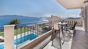 Uma varanda com piscina, móveis de exterior e vista para o mar e montanhas.
