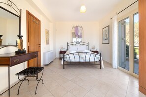 A bedroom with a bed, a desk, a chair, a radiator, and a window.
