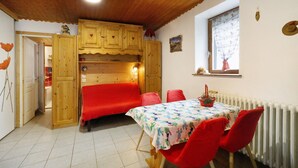 A dining area with a table, chairs, and a red sofa. - Apartment 'Studio Cabine - Les Ecrins 2' with Mountain View and Wi-Fi (Valloire)