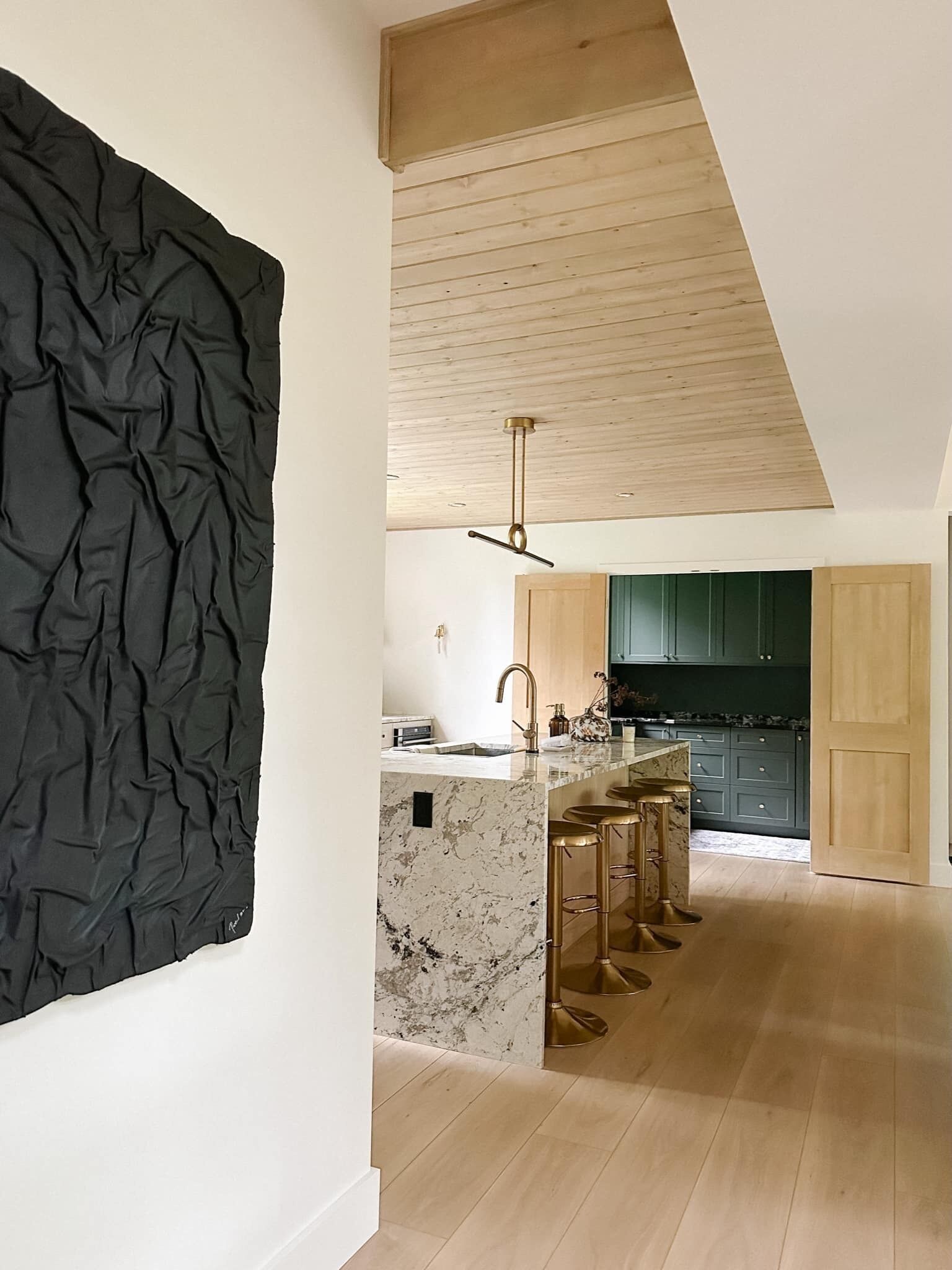 A modern kitchen with a marble island, wooden cabinets, and a pendant light.
