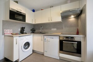 Une cuisine compacte équipée d’un lave-linge, d’un lave-vaisselle, d’un four et d’un four à micro-ondes.