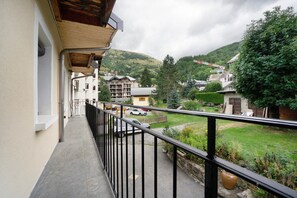 A balcony with a metal railing overlooking a residential area with houses and a hill in the background. - Apartment 'Les Ecrins 3' with Mountain View (Valloire)