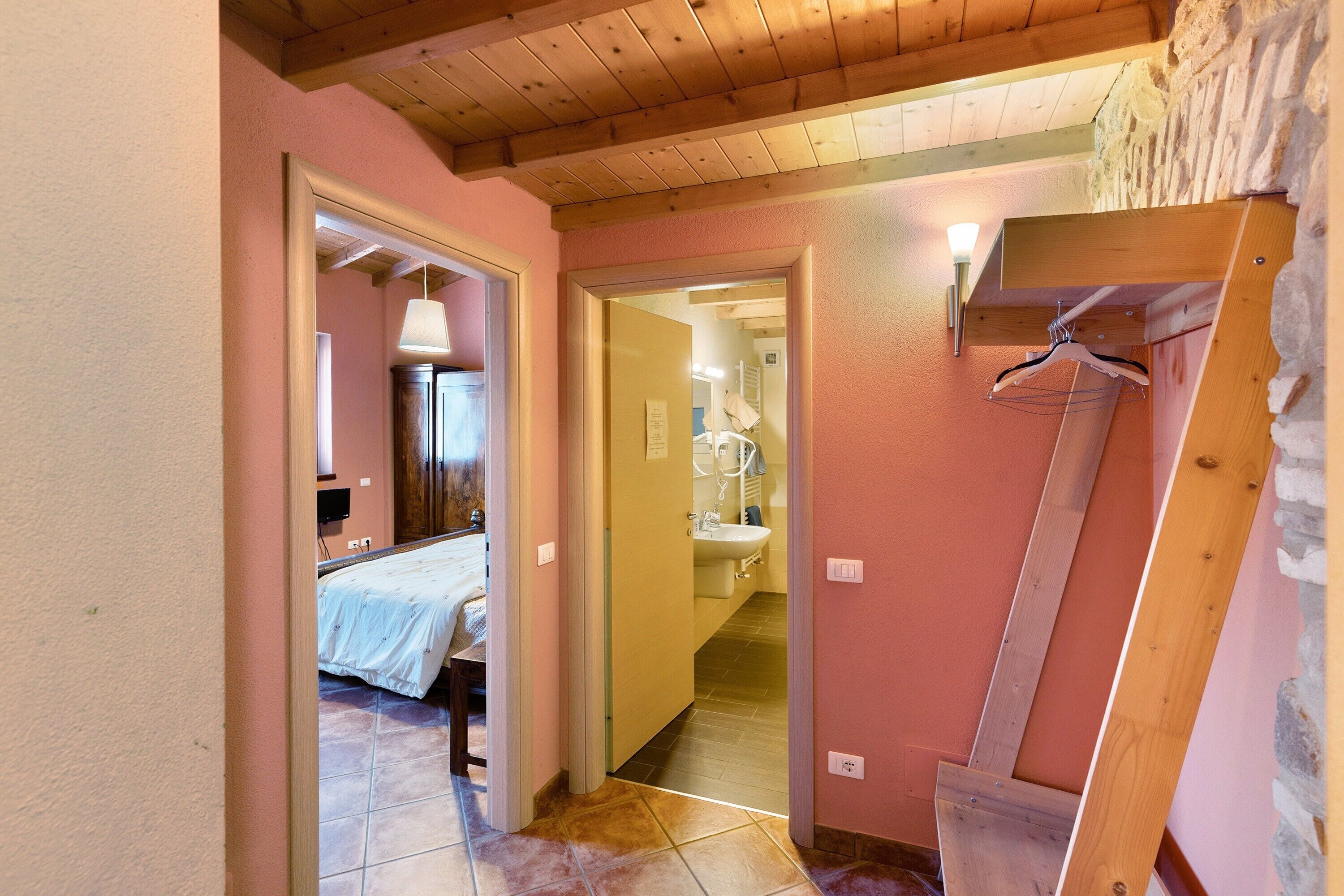 Un couloir étroit comprenant un lit, une salle de bain et une structure en poutres de bois.