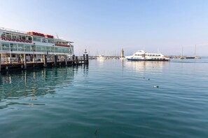 Un hotel frente al mar con un muelle, un barco blanco grande y cielo despejado.