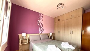 A bedroom with a bed, nightstands, a wardrobe, and a decorative wall.