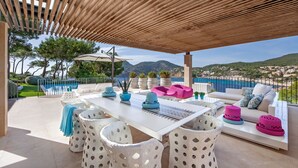 An outdoor patio with a wooden pergola, white furniture, and a view of the sea and mountains. - Villa 'Oasis Del Mar - Splendid' with Sea View, Wi-Fi and Air Conditioning (IB)