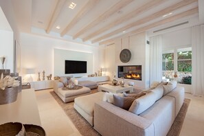 A modern living room with a fireplace, comfortable seating, and a large TV. - Villa 'Oasis Del Mar - Splendid' with Sea View, Wi-Fi and Air Conditioning (IB)