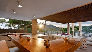 A modern kitchen with a wooden island, a dining area with a view, and a balcony with outdoor seating. - Villa 'Oasis Del Mar - Splendid' with Sea View, Wi-Fi and Air Conditioning (IB)