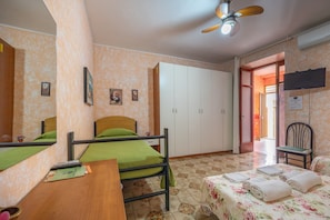 Une chambre avec un lit superposé, un bureau, une chaise, une télévision et une armoire.
