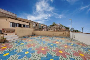 A rooftop with colorful floral tile flooring, a staircase, and a satellite dish. - Room 'Appartamento 1 - Stanza 13' with Shared Terrace, Wi-Fi and Air Conditioning (Ficarra)