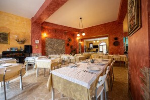 A restaurant with multiple tables, a stone wall, and a large mirror.
