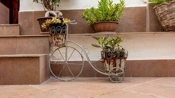 A bicycle with potted plants attached to it, positioned on a tiled outdoor area.