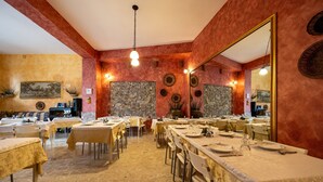 A restaurant with multiple tables, stone walls, and a large mirror. - Room 'Appartamento 3 - Stanza 31' with Shared Terrace, Wi-Fi and Air Conditioning (Ficarra)