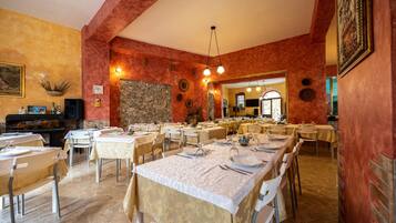 Un restaurant avec plusieurs tables, un mur en pierre et un grand miroir.