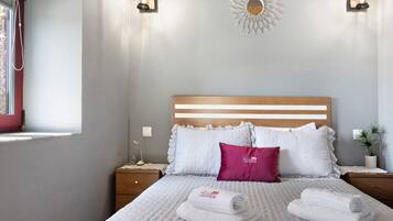 A neatly made bed with white and pink pillows, a wooden headboard, and two bedside tables with lamps.