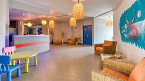 Een hotellobby met rieten meubels, een receptiebalie en hanglampen.