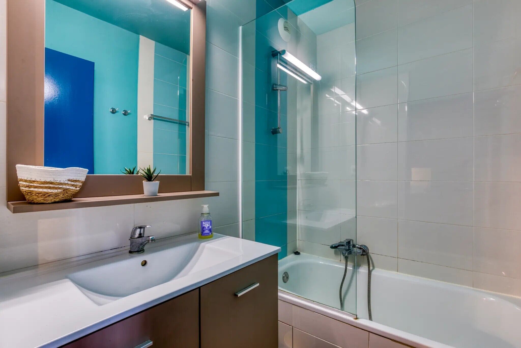 A bathroom with a white sink, a mirror, a glass-enclosed shower, and a bathtub.