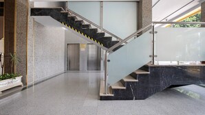 Un interior moderno con una escalera de mármol, barandales de vidrio y un piso limpio y pulido.
