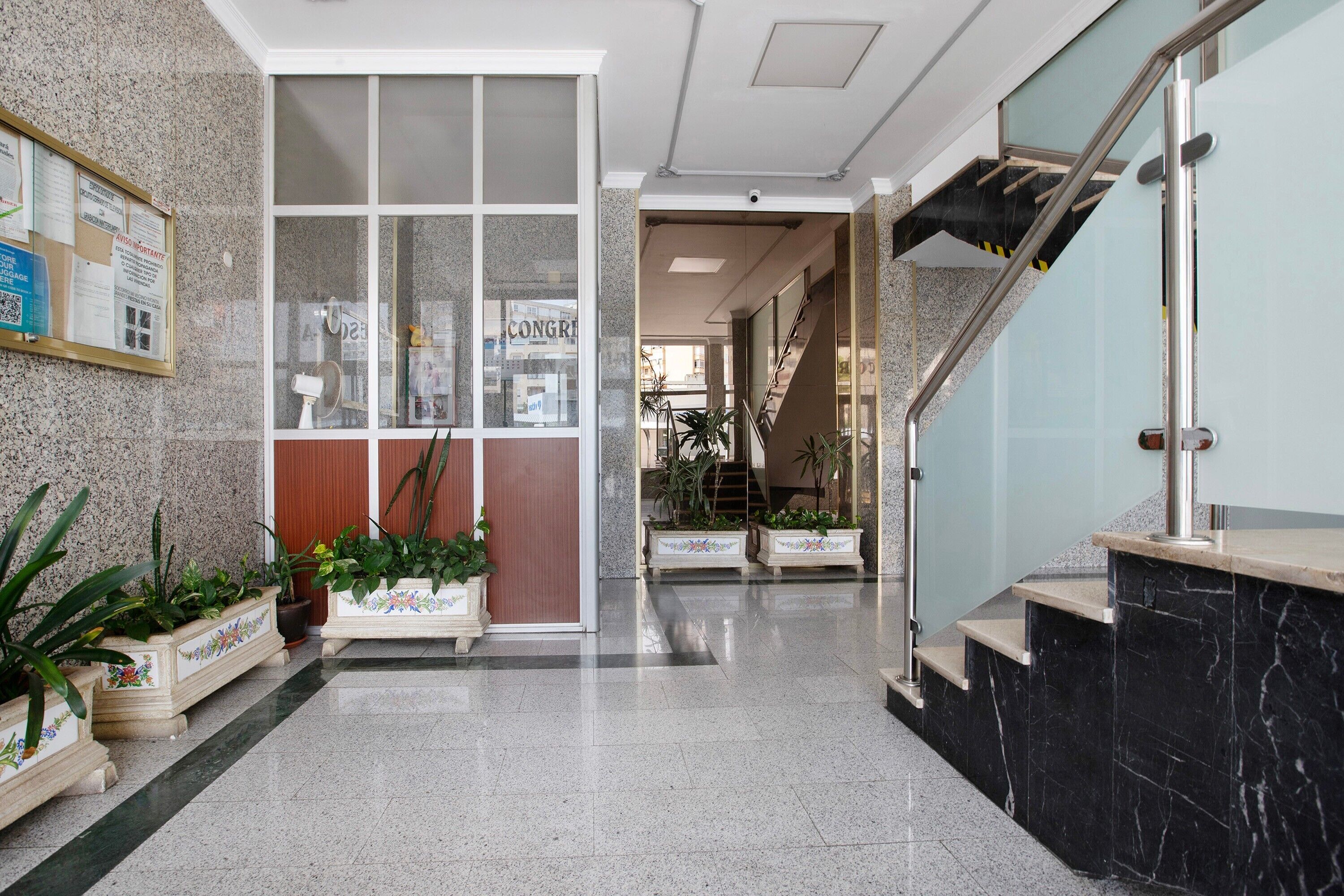 A lobby with a reception desk, a bulletin board, and a staircase leading to another floor.