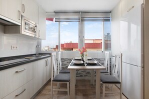 Moderni keittiö, jossa on ruokailutila, sisäänrakennettu uuni ja näkymä kaupunkiin.