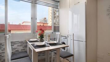 Cocina compacta con comedor, lavadora y refrigerador.