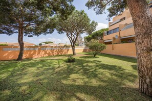 A courtyard with trees, a building with balconies, and a well-maintained lawn.