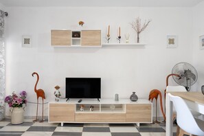 Una sala de estar moderna con un televisor de pantalla plana, armarios de madera, un comedor y elementos decorativos.