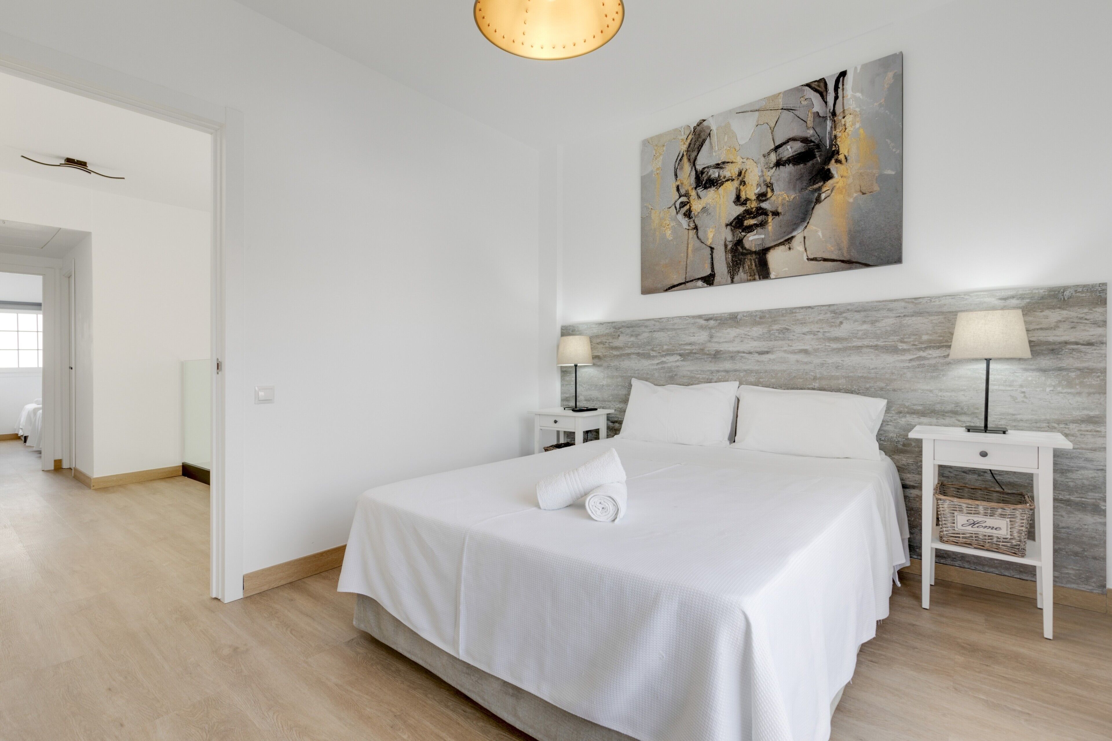 Een moderne hotelkamer met een groot bed, twee nachtkastjes, een hoofdbord en een schilderij aan de muur.