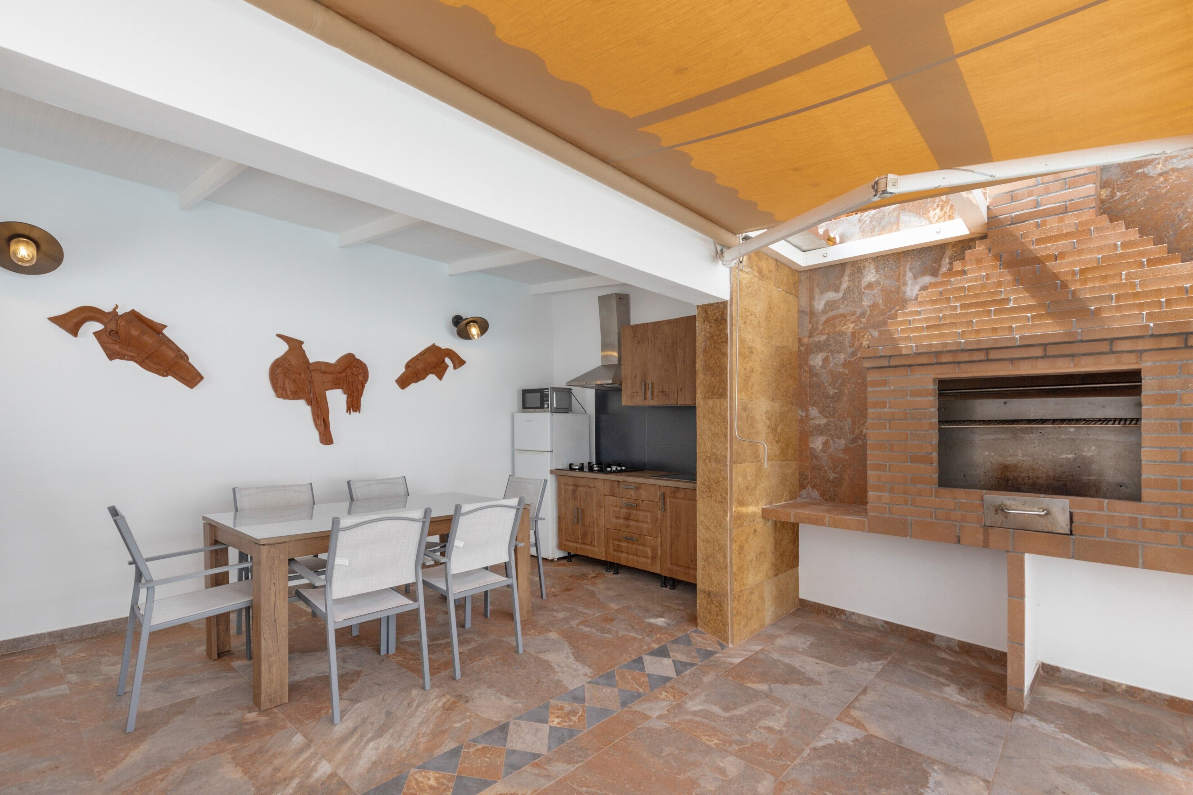 A modern kitchen with a brick oven, white cabinetry, and a dining area with a table and chairs.