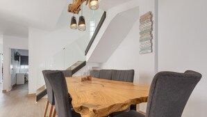 Un comedor con una mesa de madera, sillas tapizadas en gris y una escalera.