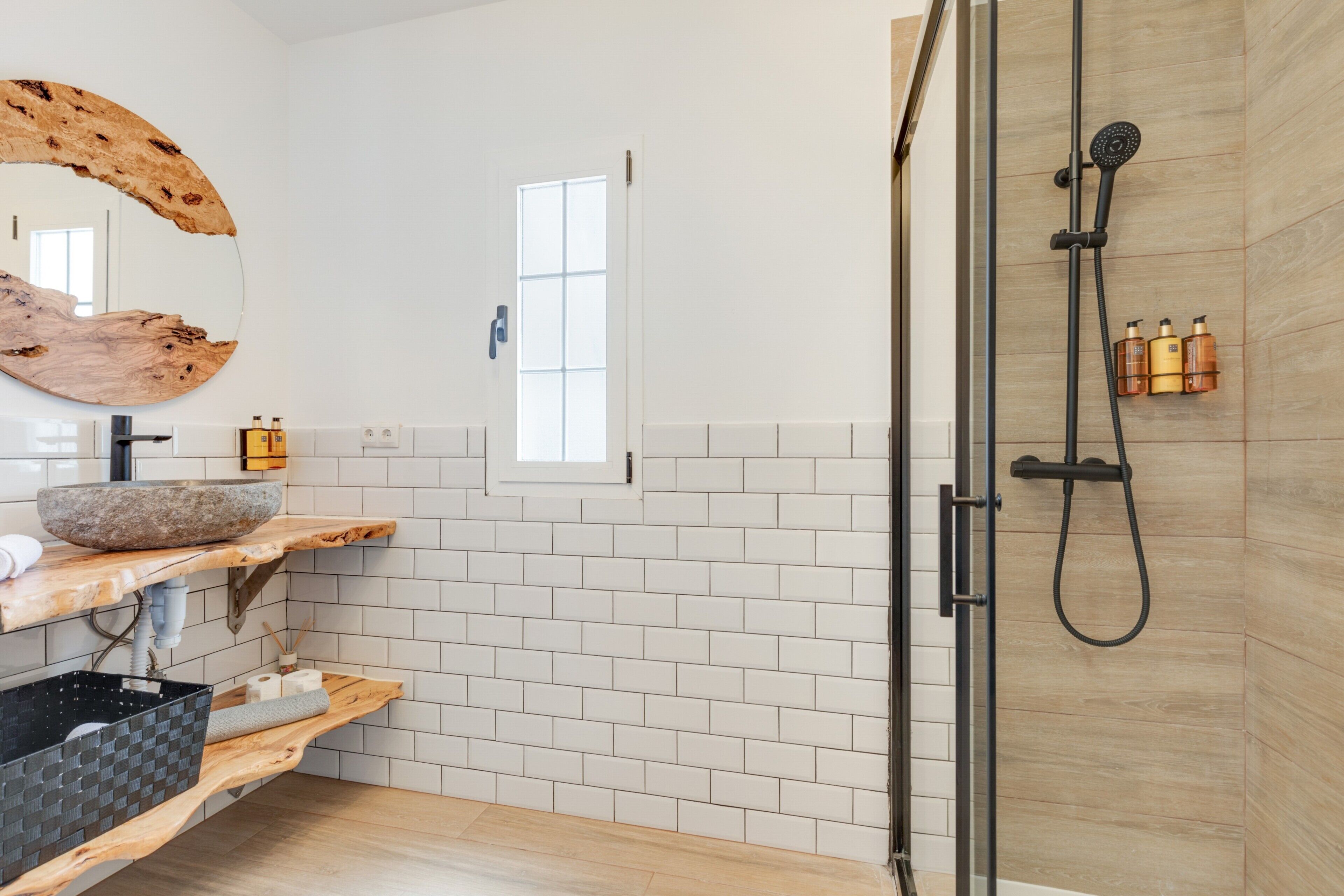 Ein modernes Badezimmer mit einem Holzlagerflansch, einem großen Spiegel, einer Duschkabine und einem Fenster.