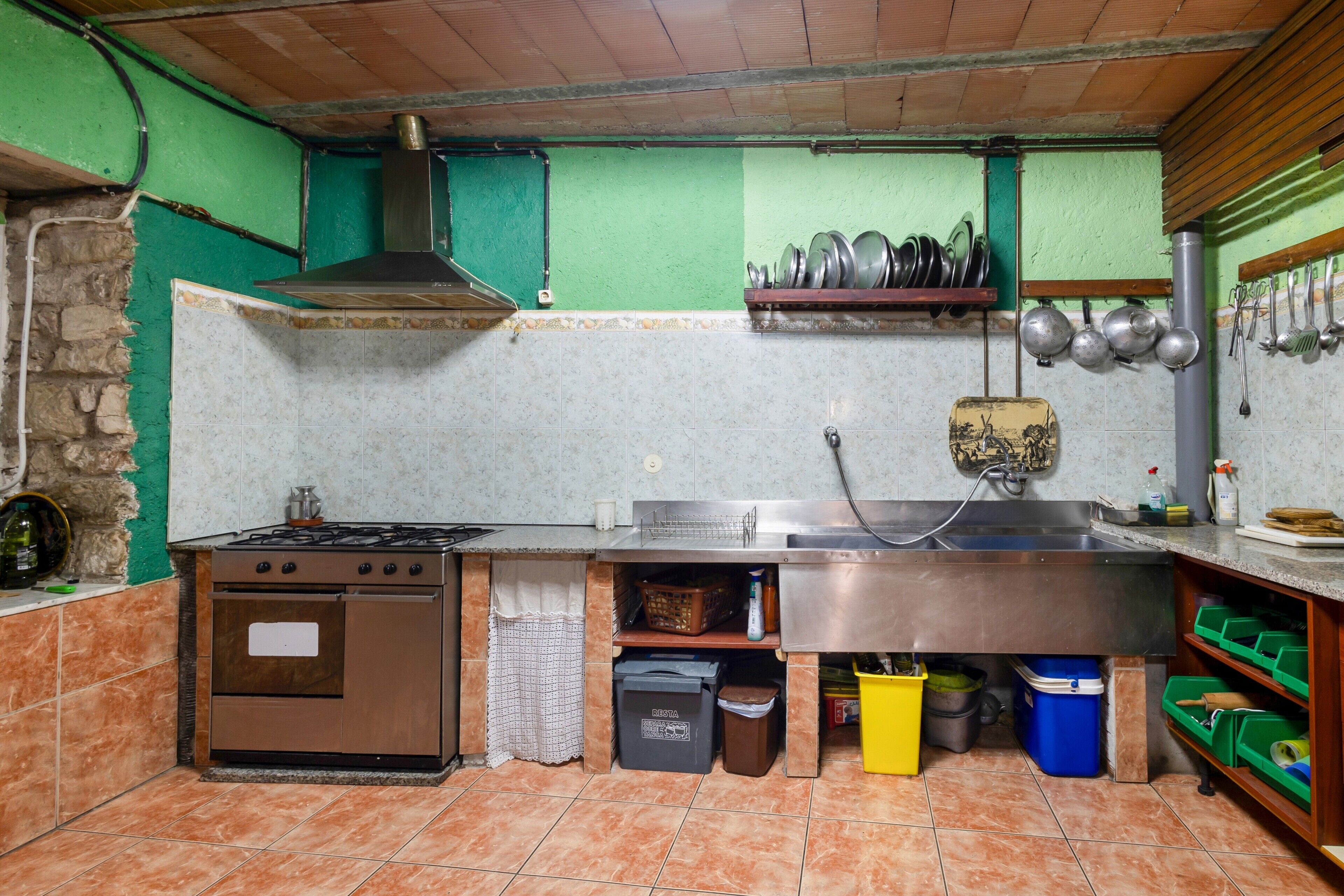 Una cocina con estufa, pileta y diversos utensilios.