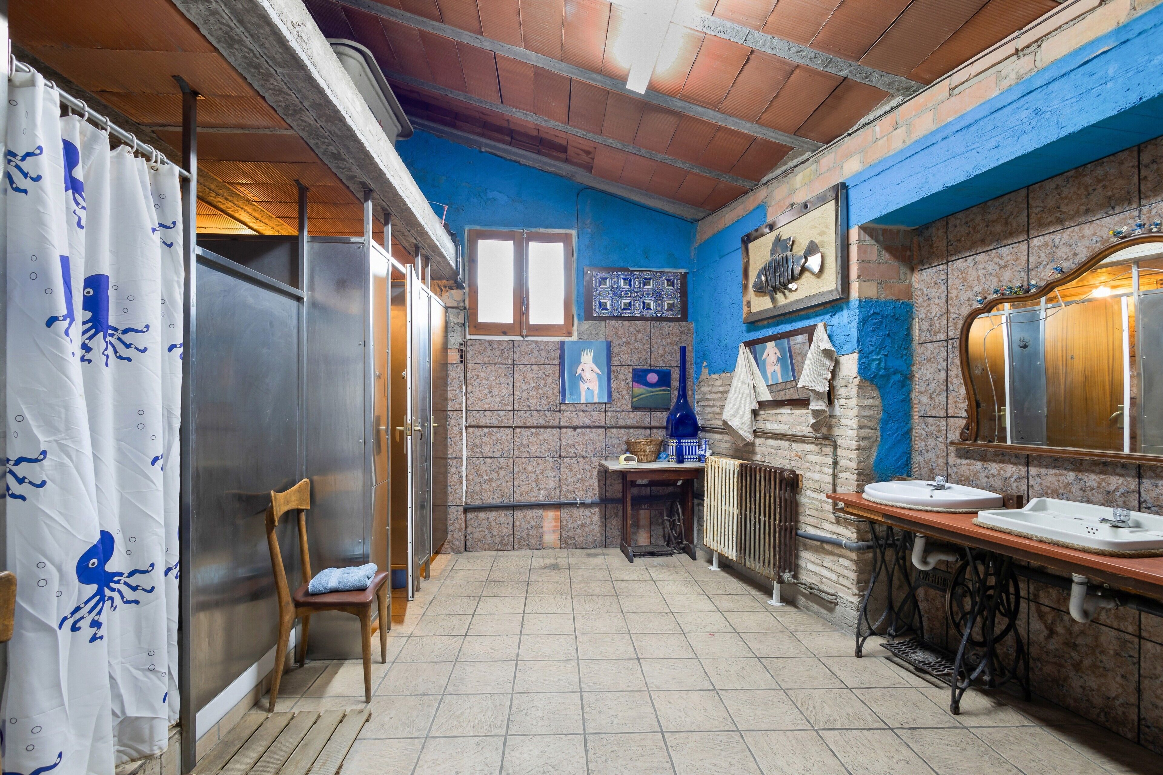 Un baño con ducha, dos lavamanos, un espejo y un perchero para toallas.