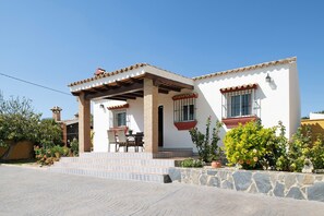 Una casa de dos pisos con un patio, escalones de piedra y plantas en macetas.