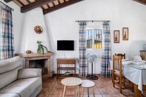 Una sala de estar con sofá, chimenea, televisor, comedor y ventana con cortinas.