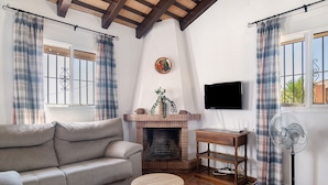 Sala de estar con sofá, chimenea, televisor y ventilador.