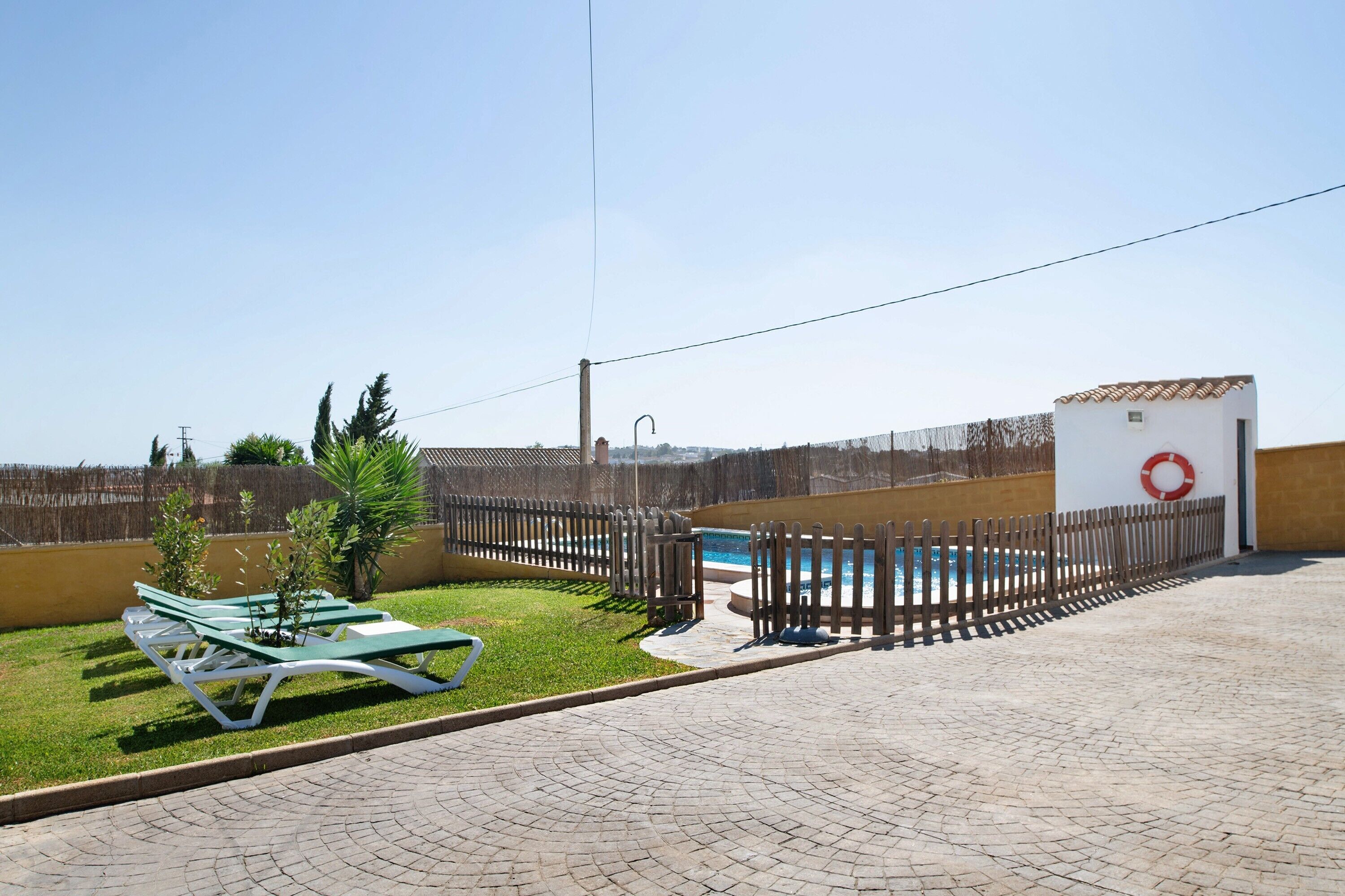 A pool area with a fence, a lifebuoy, and a picnic table.