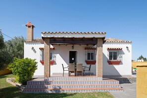 A two-story building with a covered patio, a chimney, and a small garden area.