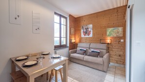 Un coin repas avec une table en bois dressée pour quatre personnes, un canapé et un mur en bois orné d’œuvres d’art.