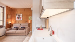 Une salle de bain moderne avec un lavabo blanc, un mur en bois et un canapé beige dans le salon attenant.