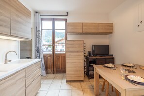 Una cucina moderna con mobili in legno, forno a incasso e zona pranzo con tavolo apparecchiato per due.
