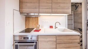 Une cuisine moderne avec des meubles en bois, un four en acier inoxydable et un plan de travail blanc.